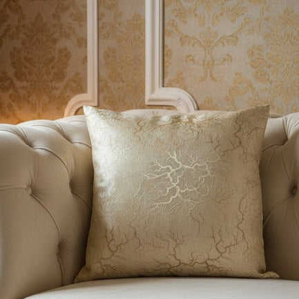 Decorative pillow on a beige sofa with ornate wall paper