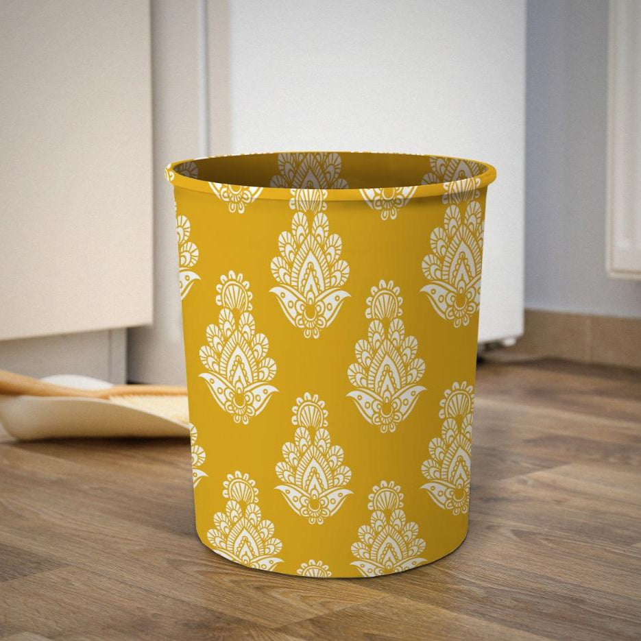 Yellow trash bin with white floral pattern on a wooden floor.