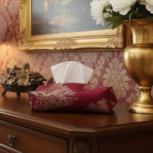 Tissue box on a wooden surface with decorative elements including a gold vase and framed artwork.