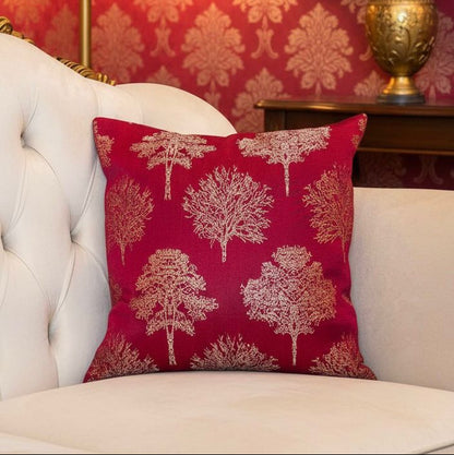 Decorative pillow with tree pattern on a red sofa against a red wall with floral wallpaper.